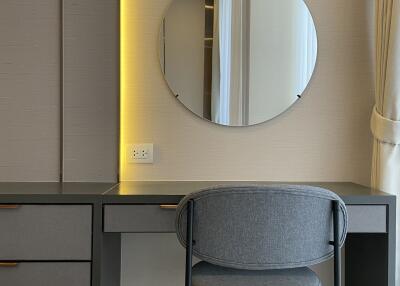 A modern bedroom workspace with a sleek desk, chair, and round mirror