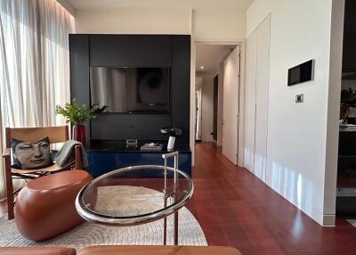 Modern living room with TV, accent chair, and clear coffee table