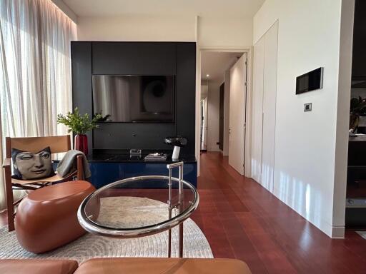 Modern living room with TV, accent chair, and clear coffee table