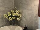 Bathroom with marble tiles, a bathtub, a vase with flowers, and a sink