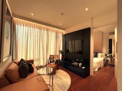 Modern living room with large window, brown sofa, circular coffee table, TV, and access to bedroom