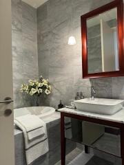 Modern bathroom with marble tiles, a bathtub, and a vanity with a mirror