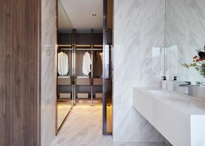 Modern bathroom with dual sinks and view into a walk-in closet