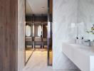 Modern bathroom with dual sinks and view into a walk-in closet