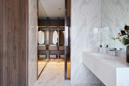 Modern bathroom with dual sinks and view into a walk-in closet