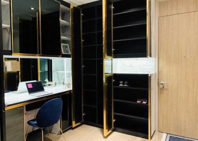 Modern home study area with built-in black and gold shelves, wooden door, and workspace