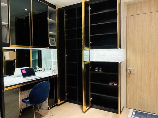 Modern home study area with built-in black and gold shelves, wooden door, and workspace