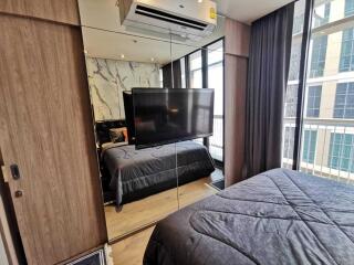 Modern bedroom with a large mirror, bed, and wall-mounted TV