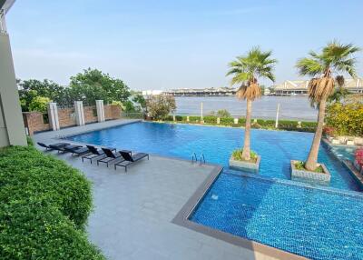 Outdoor swimming pool area with lounge chairs and palm trees overlooking a body of water