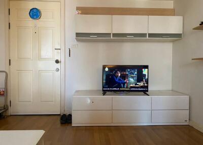 Living room with TV, wall-mounted cabinets, and wooden flooring