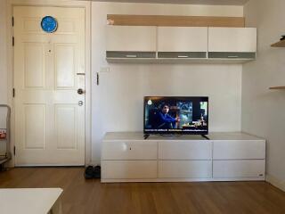 Living room with TV, wall-mounted cabinets, and wooden flooring