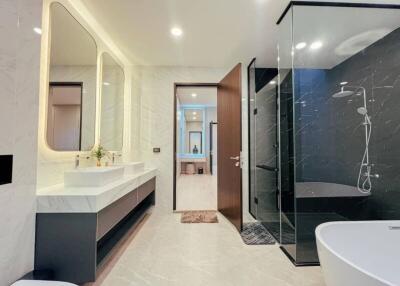 Modern bathroom with dual sinks, large mirror, and glass-enclosed shower