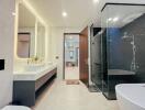 Modern bathroom with dual sinks, large mirror, and glass-enclosed shower