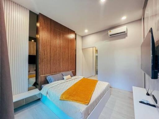 Spacious modern bedroom with wooden accent wall and mounted air conditioner