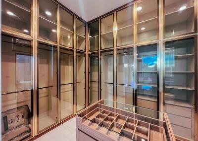 Spacious walk-in closet with glass-paneled doors and built-in shelving