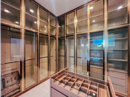 Spacious walk-in closet with glass-paneled doors and built-in shelving