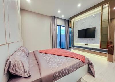 Modern bedroom with a large bed, wall-mounted TV, and stylish lighting