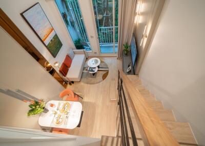 Modern living room with high ceilings, staircase, dining area, and large window.