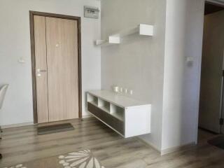 Entryway with a wooden door, white walls, and a floating shelf