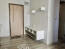 Entryway with a wooden door, white walls, and a floating shelf