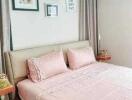 Comfortable bedroom with pink bedding and framed pictures on the wall