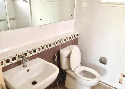 A clean and well-lit bathroom with a sink, toilet, and a mirror