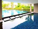 Swimming pool with stepping stones, surrounded by greenery and a basketball hoop