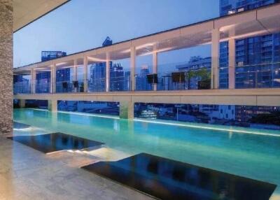 Modern condominium with rooftop swimming pool at sunset, overlooking the city skyline.