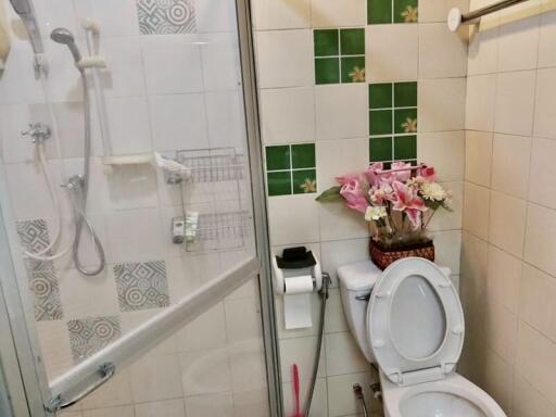 Clean and organized bathroom with shower and floral arrangement