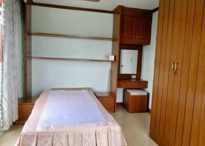 Single bed with wooden furniture and built-in shelves