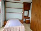 Single bed with wooden furniture and built-in shelves