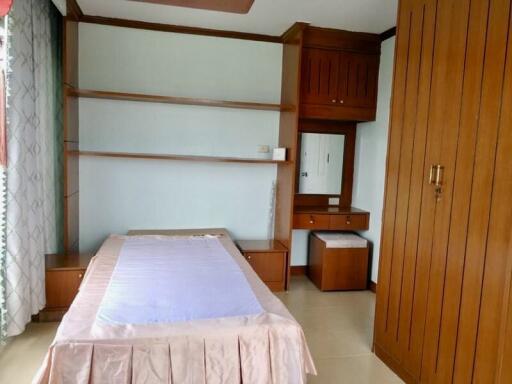 Single bed with wooden furniture and built-in shelves