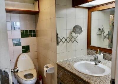 Bathroom with a toilet, sink, mirror, and tiled backsplash