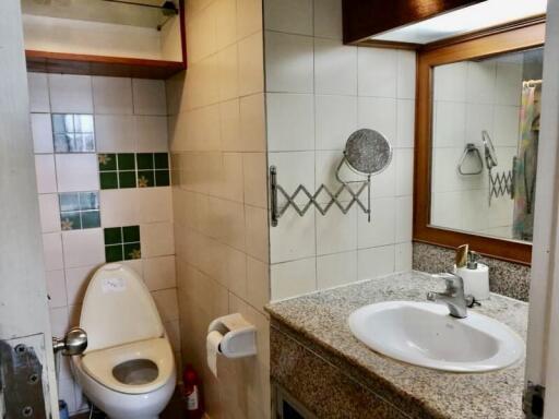 Bathroom with a toilet, sink, mirror, and tiled backsplash