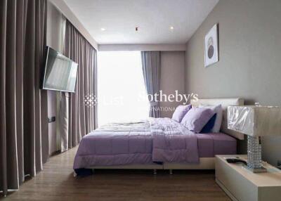 Modern bedroom with a king-sized bed, bedside table, and wall-mounted TV.