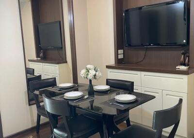 Modern dining area with a wall-mounted TV, rectangular table, and four chairs