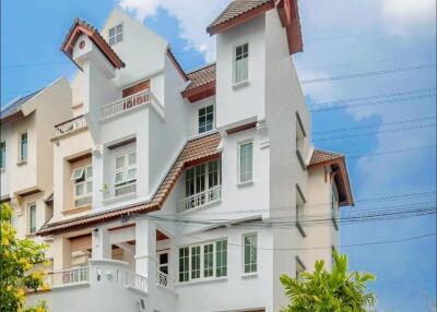 Three-story modern residential building with balconies and carport