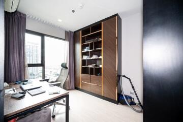 Modern home office with wooden bookshelf, desk, and city view