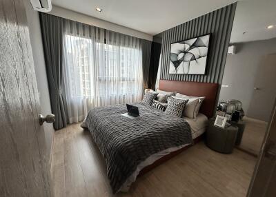 Modern bedroom with large window, bed, and decorative elements