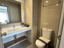 Modern bathroom with toilet, sink, mirror, and light brown tiled walls.