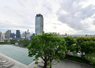 City skyline view from a high-rise building, featuring a lush green garden and infinity pool