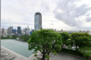 City skyline view from a high-rise building, featuring a lush green garden and infinity pool