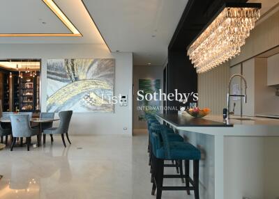 modern living and dining area with large chandelier, bar seating, and artwork