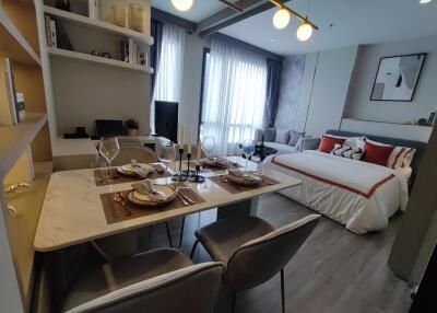 A modern studio apartment with a dining area and bed.