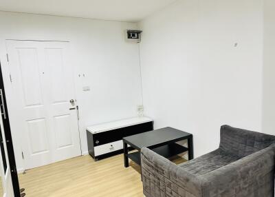 Small living room with grey chair, black coffee table, and white wall