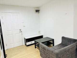 Small living room with grey chair, black coffee table, and white wall