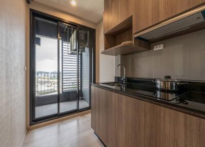 Modern kitchen area with wooden cabinetry and a view to the outside balcony