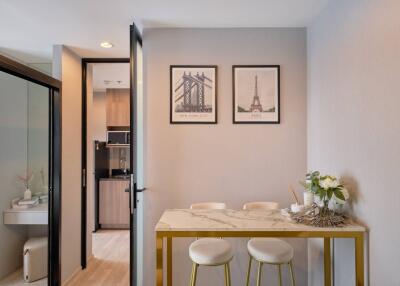 Dining area with two framed pictures on the wall, a marble-top table, and two stools