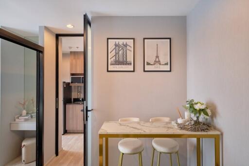 Dining area with two framed pictures on the wall, a marble-top table, and two stools