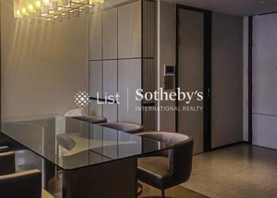 Modern dining area with glass table and upholstered chairs, featuring contemporary lighting and built-in cabinetry